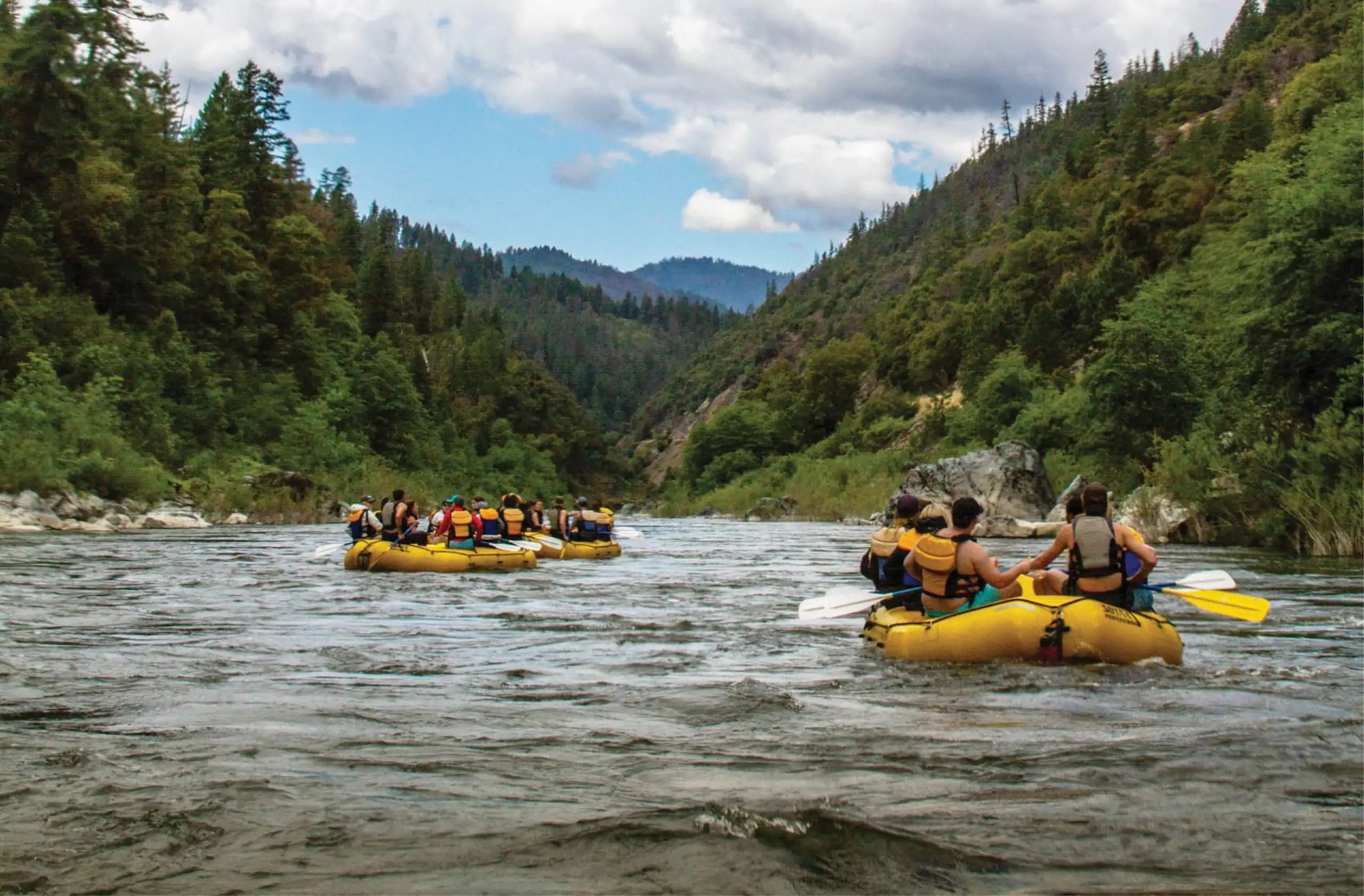 Group of people on rafts, floating on the Klammoth River through the mountains at JH Ranch California